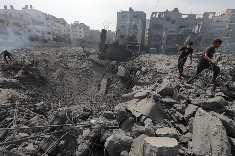 Palestinians walking past a bomb crater following an Israeli air strike in Gaza City this week.